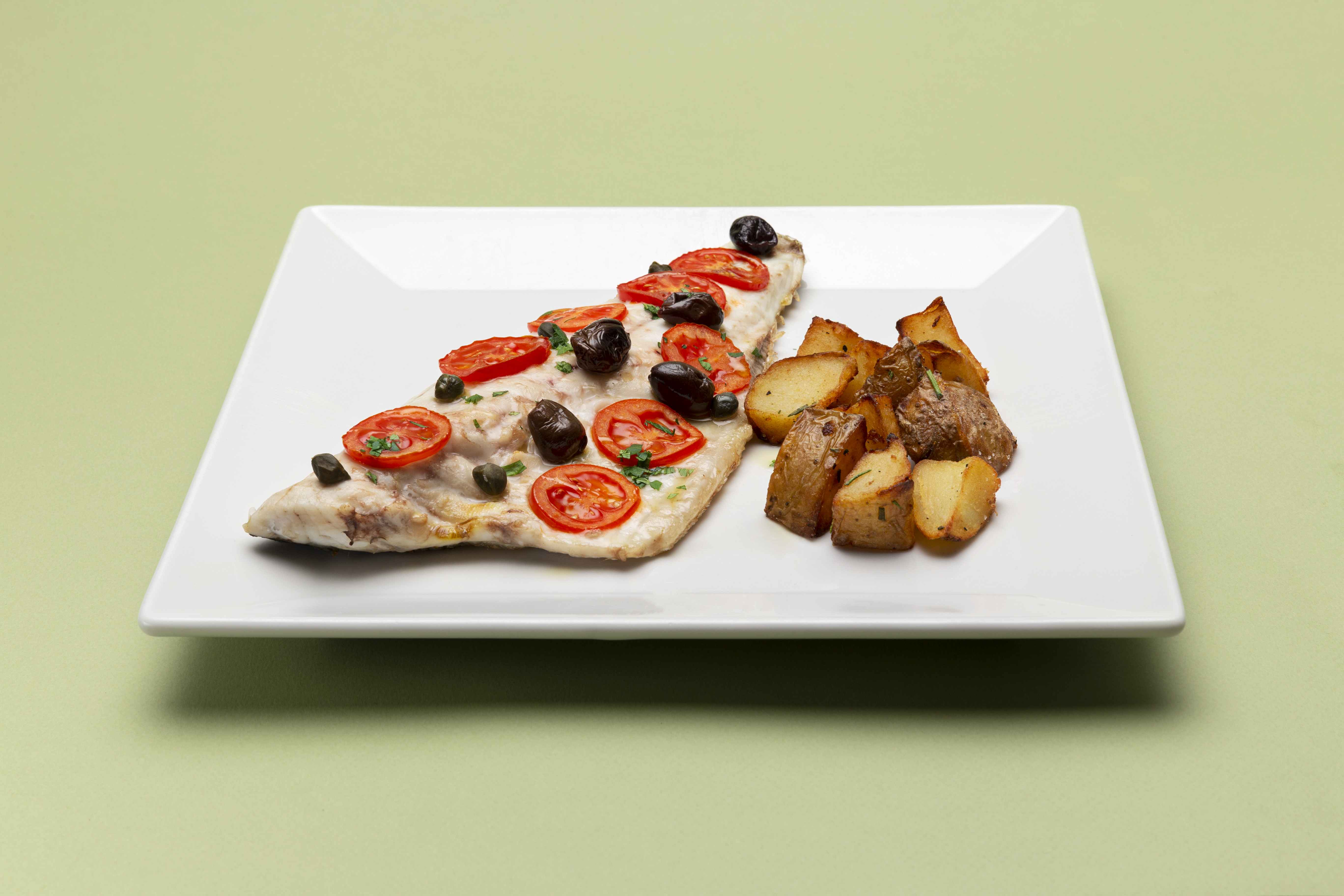 Filetto di spigola con pomodorini, olive, capperi e pinoli